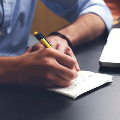 Man taking notes on pad and computer